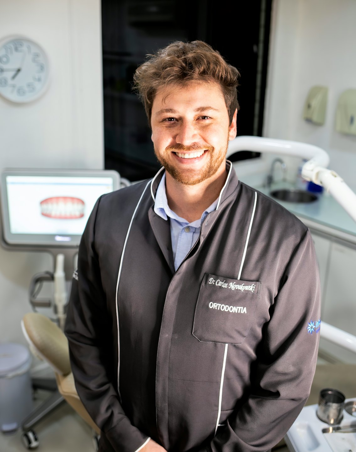 Uśmiechnięty dentysta w nowoczesnej klinice stomatologicznej ogląda model 3D.