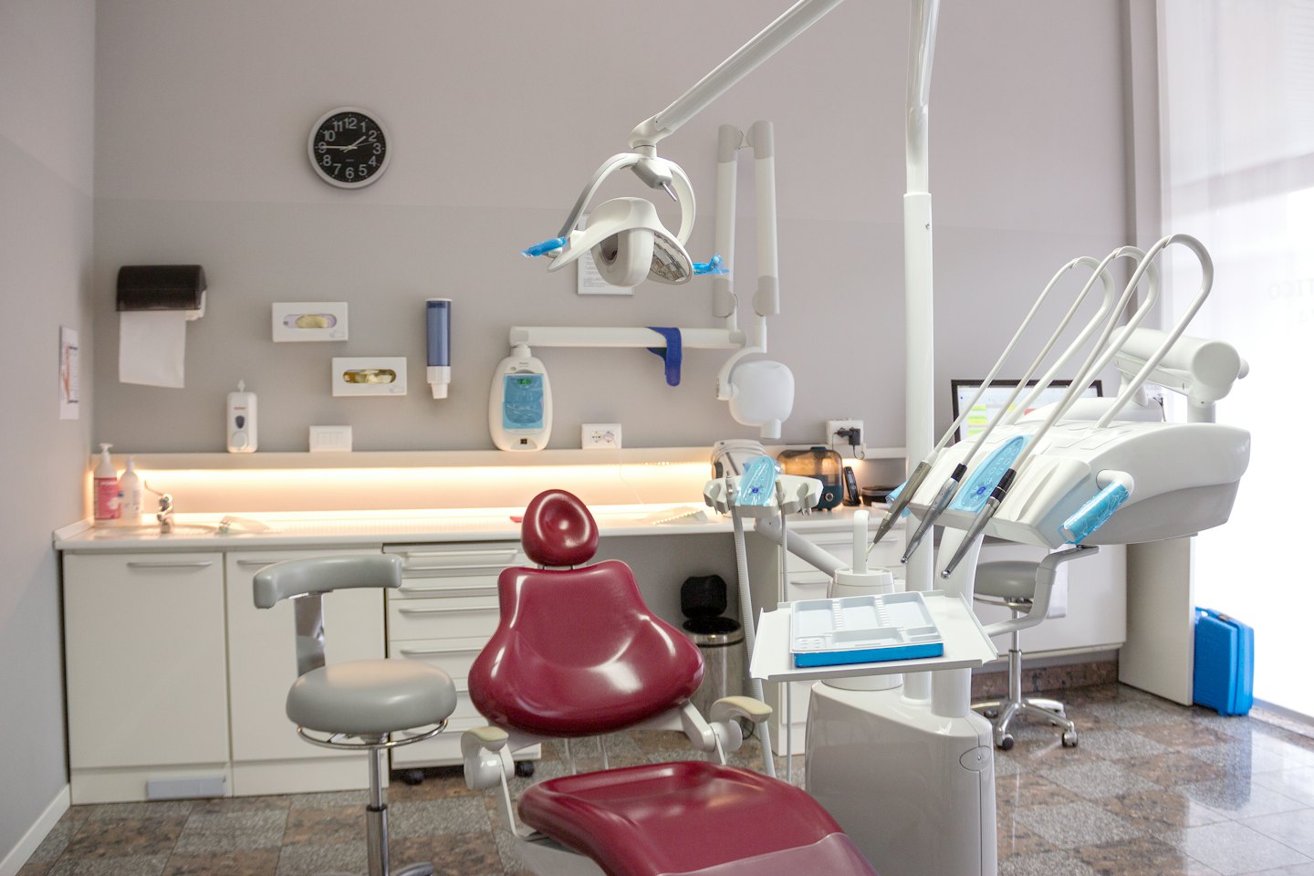 Nowoczesny gabinet dentystyczny z czerwonym fotelem i instrumentami medycznymi.